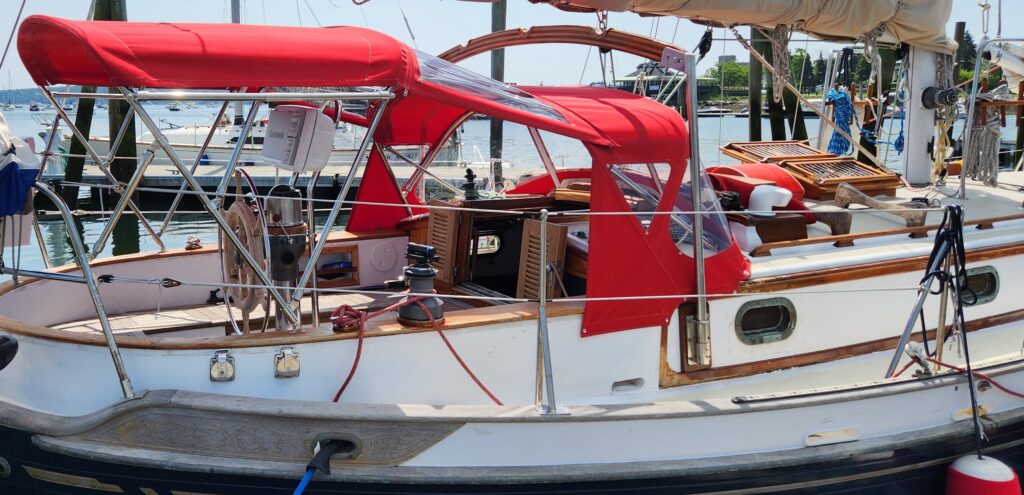 Bright red dodger, bimini and connector on white sail boat.